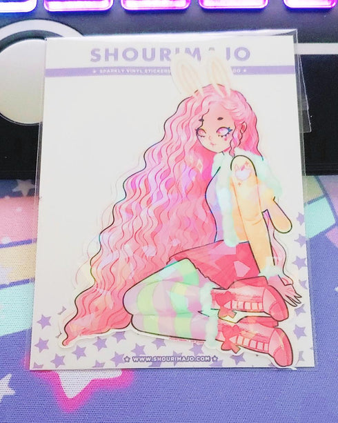 A teenage looking kawaii manga girl who is wearing white bunny ears and has long pink wavy hair. She is sitting with her knees bent and her legs off to the side. She is wearing pink and green striped leggings, a pink skirt, pink high heeled boots, and a yellow furry light jacket. This digital art piece is printed on a broken glass holographic vinyl sticker.