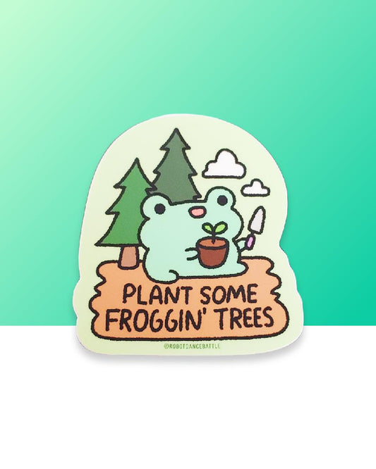 A cute kawaii smiling frog froggie holding a gardening spade and a plant with dirt and a leaf sitting in camp dirt with two pine trees behind him and two clouds in the sky on a vinyl sticker. The sticker reads "Plant some froggin' trees." Designed by small business robot dance battle