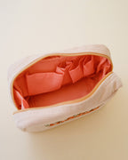 Bolsa de maquillaje de pana con bordado floral rojo y naranja en color arena blanca