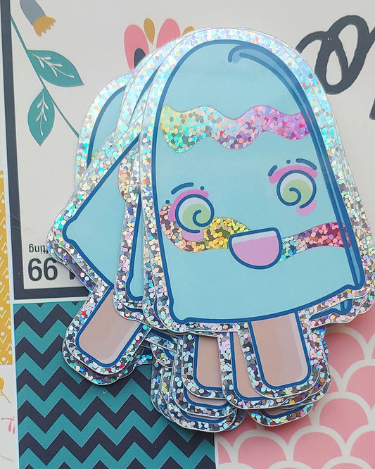 A pile of blue popsicle stickers with light green swirly eyes, hot pink eye shadow, and light pink rosy cheeks.  The popsicle has a huge kawaii grin on its face.  This glossy vinyl glitter sticker has a glitter border, and two rainbow wavy glitter line details across it's body.  It has a beige stick at the bottom.