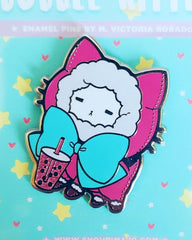 An up close of: A white kitty cat in a hot pink sweater hoodie pull over with fur lined hood with a teal green giant bow. The kitten is drinking a hot pink boba drink. All of this art is on a had enamel pin and mint green "bubble kittea" backing card.