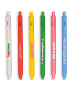 A green click gel pen that reads You're the cherry on top", next to a yellow pen that reads "stay sunny", next to a pink pen that reds "life's a picnic", next to a blue pen that reads "let me write that down", next to a white pen that reads "keep it easy", next to a orange pen that reads "let the delight in" all on a white background