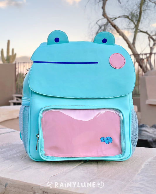 An extremely high quality blushing frog ita mint green back pack with dark blue details and pink cheeks.  Comes with two inserts: one pink and the other dark blue for swappable pin displays.  Extremely spacious inside and includes two side pockets.