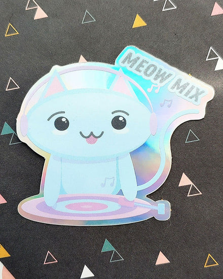A holographic and reflective blue, purple, and grey pastel kawaii kitty cat dj wearing headphones and touching a record player with its tongue sticking out.  It reads "meow mix" as a play on words and is a high quality vinyl sticker.