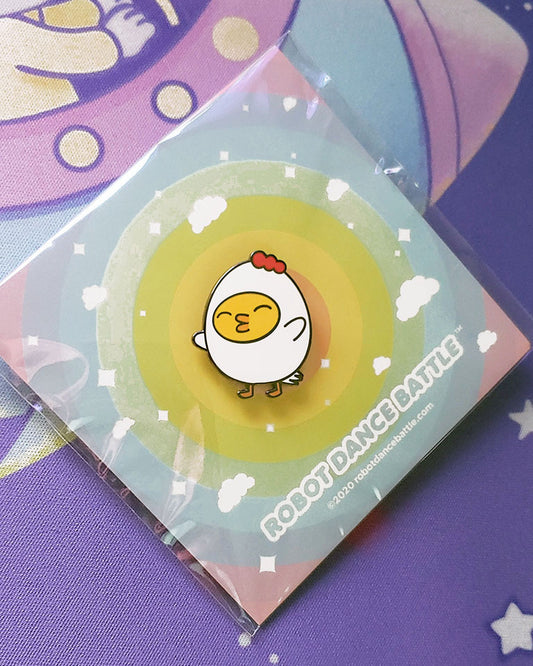 A little yellow ducky dressed up as grumpy chicken and enamel pin using the colors yellow, red, and white. Designed by small business robot dance battle