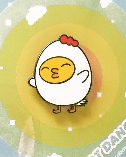 A little yellow ducky dressed up as grumpy chicken and enamel pin using the colors yellow, red, and white. Designed by small business robot dance battle