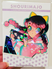 A pink and black gradient/ombre haired girl with pigtails and a pink, white, and blue pastel track jacket and black and blue track pants sits and leans back while playing her blue and black nintendo switch that is covered in kitty cat stickers.  She has blue and yellow cat ears on and yellow eyeshadow her eyes sparkle. All of this digital art piece is printed on a broken glass holographic vinyl sticker.  Attached to a white card with brand name and purple stars.  A hand is holding it.