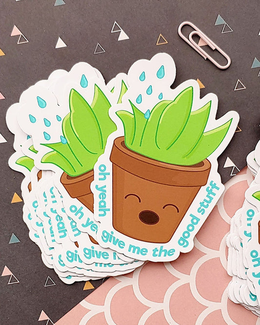 A kawaii matte vinyl sticker featuring a potted plant wanting the "good stuff." In other words, water! This is a green, brown, blue, and white succulent plant enjoying what it's getting. It reads "oh yeah give me the good stuff" This image shows a pile of the stickers