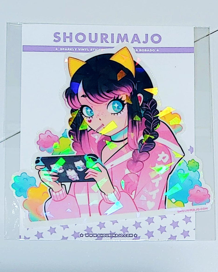An image that better shows the sparkle of the holographic broken glass. A cute kawaii manga teen gamer girl wearing a pink and white hoodie with a sucker in her mouth and yellow cat ears on her head is seen in front of cotton candy clouds of pink, yellow, blue, and green while playing on her nintendo switch with blue joy cons.  The switch has cute kitty stickers on the back.  This image is printed on broken glass holographic vinyl and is 3 inches long.